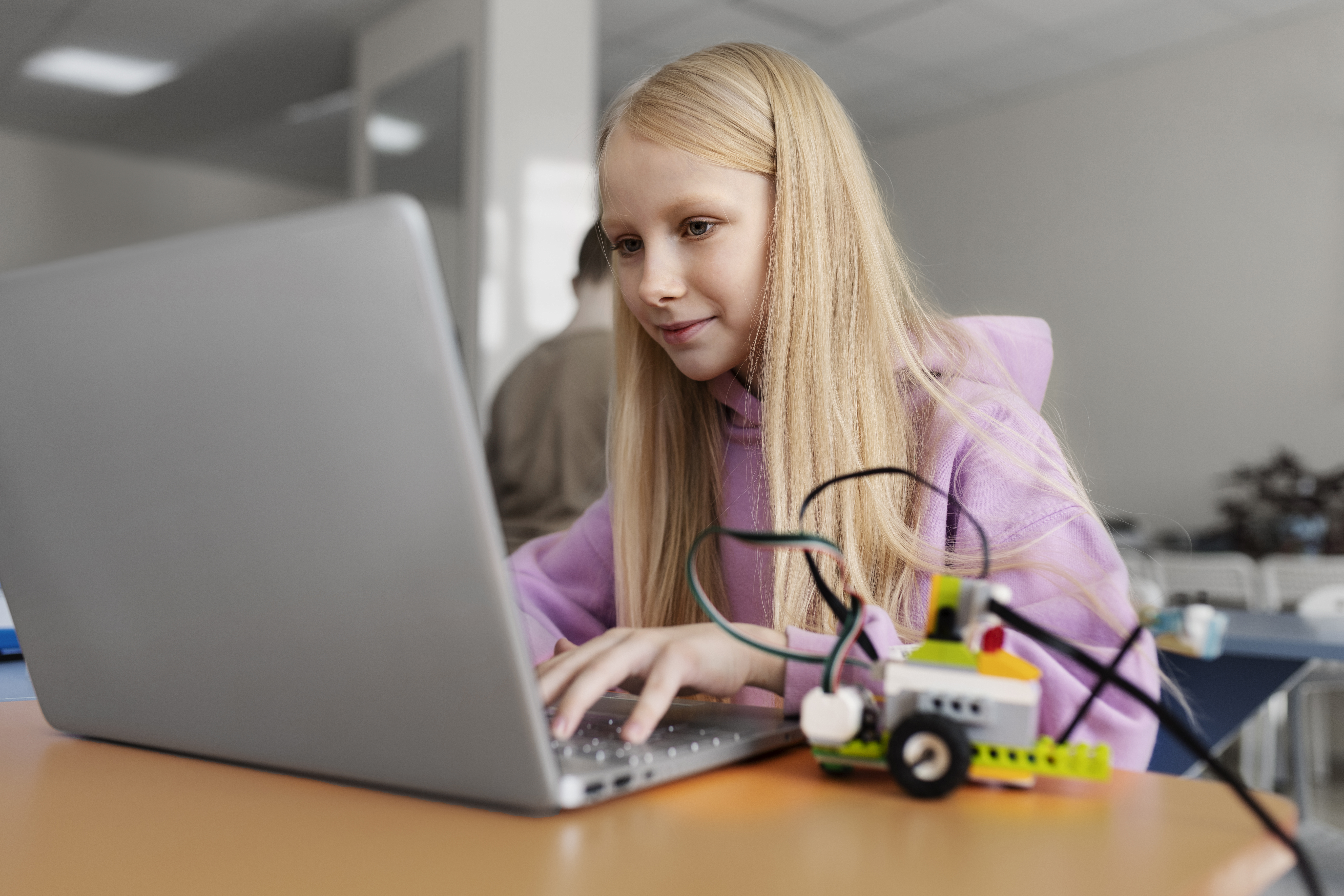 young girl using laptop electronic parts build robot